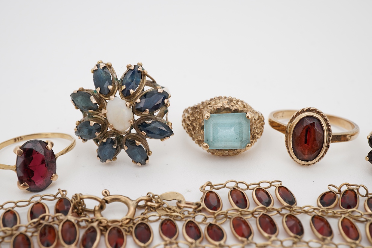 A group of jewels, comprising: two garnet cluster rings; a garnet bracelet; and a blue topaz ring, each mounted in 9ct gold, ring sizes H-M1/2, combined gross weight 13 grams; together with a marquise-shaped sapphire and